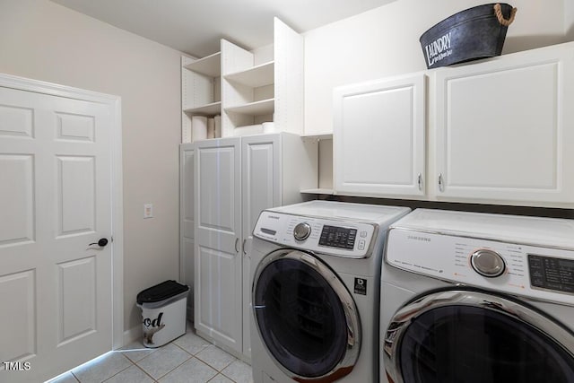 washroom with cabinet space, light tile patterned floors, and washing machine and clothes dryer