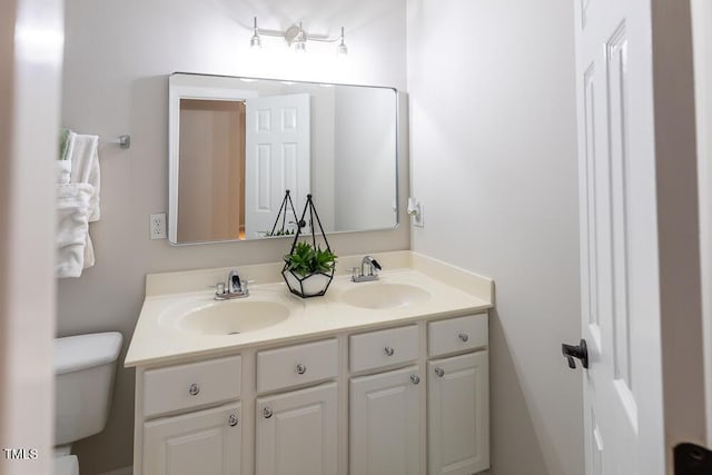bathroom with double vanity, toilet, and a sink