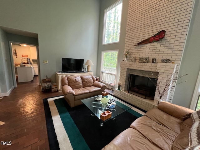 106 Orchard Rd, Henderson, NC 27536 - living area featuring healthy amount of natural light, a brick fireplace, wood finished floors, a high ceiling, and baseboards