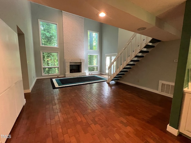 106 Orchard Rd, Henderson, NC 27536 - unfurnished living room featuring stairway, a towering ceiling, baseboards, and a brick fireplace