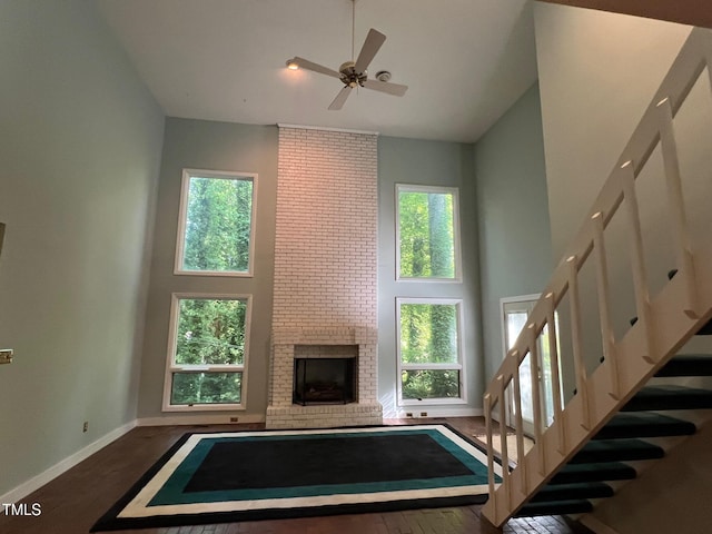 106 Orchard Rd, Henderson, NC 27536 - unfurnished living room with high vaulted ceiling, ceiling fan, baseboards, a fireplace, and stairs