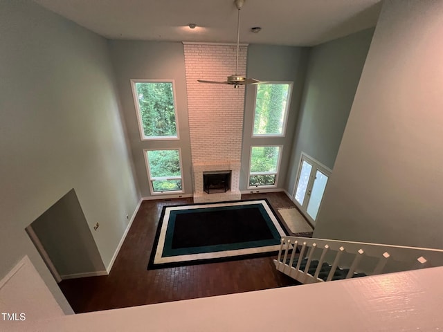 106 Orchard Rd, Henderson, NC 27536 - unfurnished living room with wood finished floors, baseboards, ceiling fan, a fireplace, and a towering ceiling