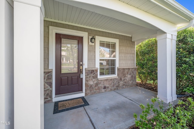 property entrance with covered porch and stone siding