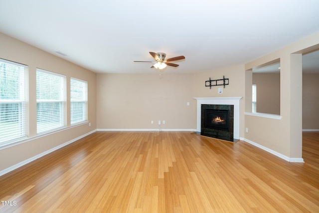 unfurnished living room featuring visible vents, baseboards, a tiled fireplace, light wood-type flooring, and a ceiling fan