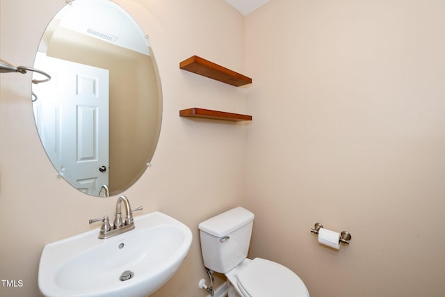 half bathroom with toilet, a sink, and visible vents