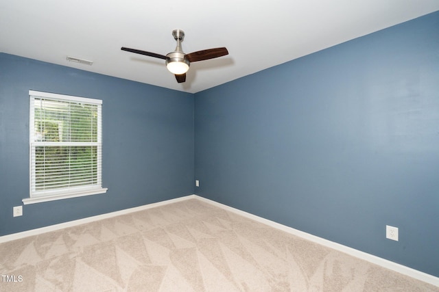 carpeted empty room with visible vents, baseboards, and a ceiling fan