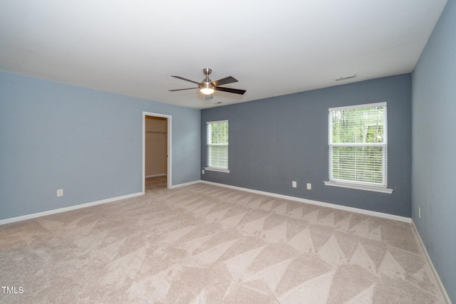 carpeted empty room with visible vents, baseboards, and a ceiling fan