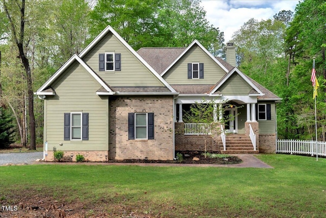 craftsman house featuring a porch, roof with shingles, a front lawn, and brick siding