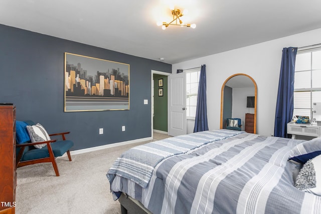 carpeted bedroom with arched walkways, baseboards, and multiple windows