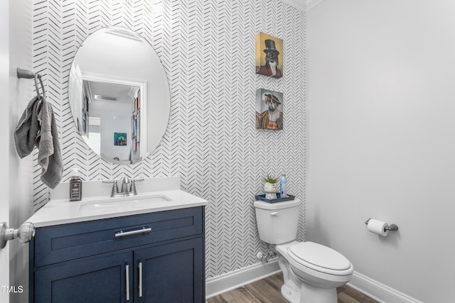 half bathroom with vanity, baseboards, toilet, and wood finished floors