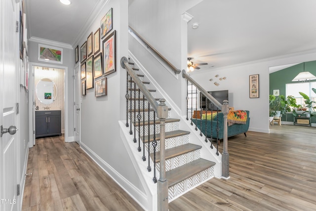 stairway featuring ornamental molding, baseboards, ceiling fan, and wood finished floors