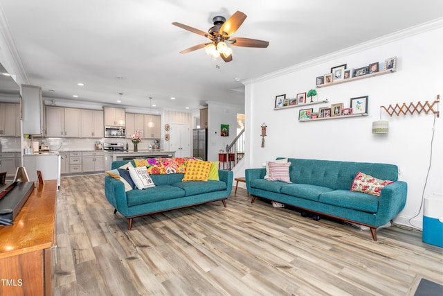 living area with ornamental molding, ceiling fan, recessed lighting, stairs, and light wood-style flooring