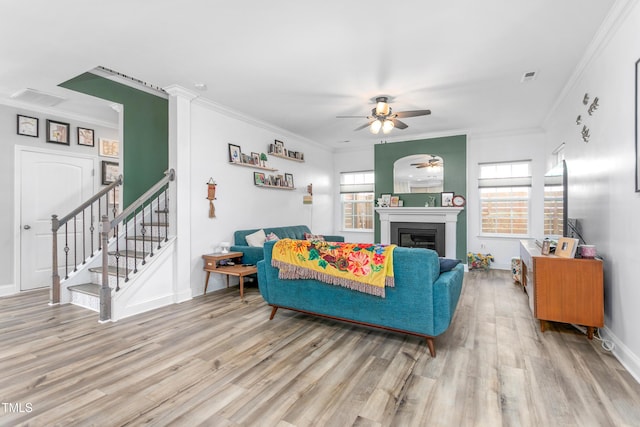 living room with visible vents, wood finished floors, ornamental molding, and ceiling fan