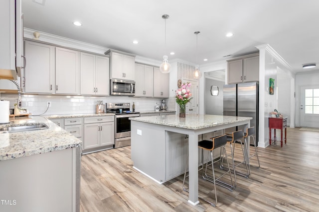 kitchen with a kitchen breakfast bar, a center island, crown molding, decorative backsplash, and appliances with stainless steel finishes