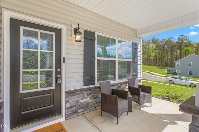 view of exterior entry featuring a porch and stone siding