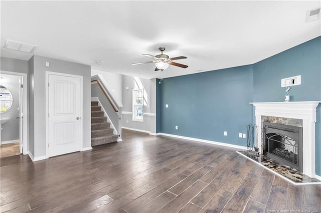 unfurnished living room with visible vents, a ceiling fan, a fireplace, wood finished floors, and stairs