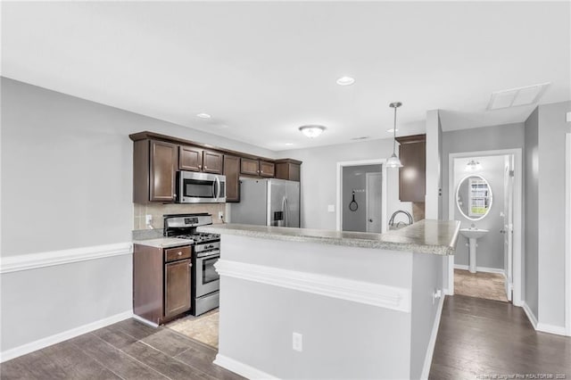kitchen featuring dark brown cabinetry, baseboards, light countertops, stainless steel appliances, and wood finished floors