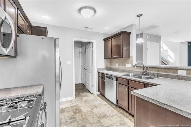 kitchen featuring dark brown cabinetry, visible vents, stainless steel appliances, a sink, and hanging light fixtures