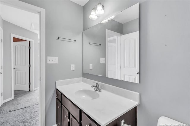 half bath with toilet, baseboards, and vanity
