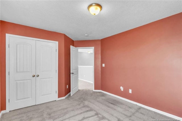 unfurnished bedroom with a closet, baseboards, carpet, and a textured ceiling