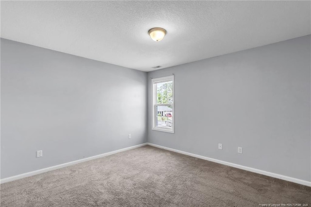 spare room with baseboards, carpet flooring, and a textured ceiling