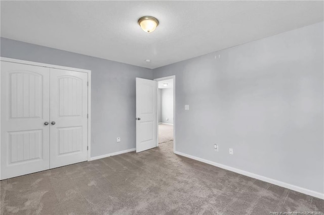 unfurnished bedroom featuring carpet floors, baseboards, and a closet