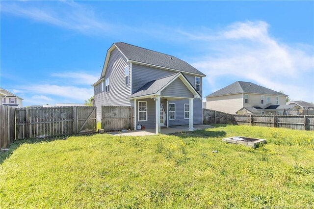 rear view of house featuring a yard, a fenced backyard, a fire pit, and a patio