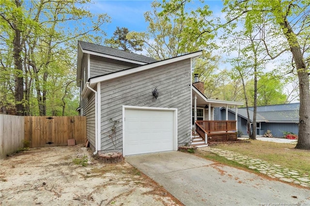 view of property exterior with an attached garage, concrete driveway, fence, and covered porch
