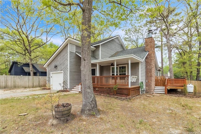 view of front facade featuring a chimney, driveway, a garage, a deck, and fence