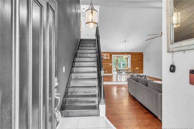 staircase with wood walls, a ceiling fan, and wood finished floors