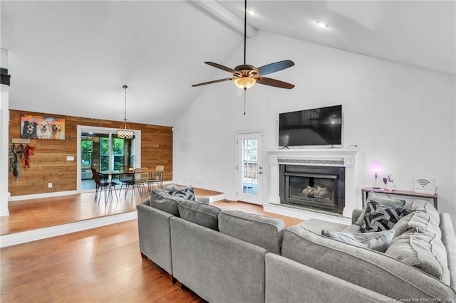 living room featuring wooden walls, beamed ceiling, wood finished floors, and a healthy amount of sunlight