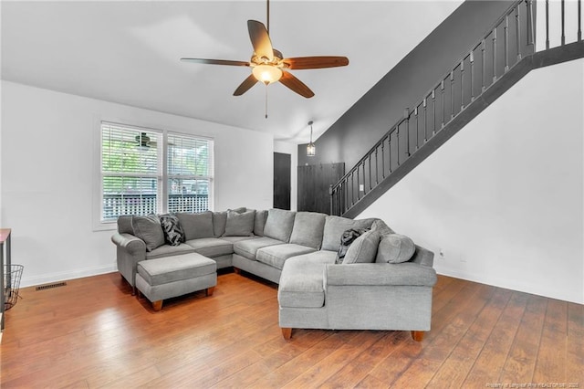 living room featuring visible vents, baseboards, a ceiling fan, stairs, and wood-type flooring