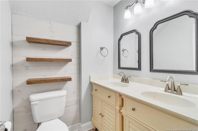full bathroom with double vanity, a textured ceiling, a sink, and toilet