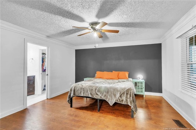 bedroom with visible vents, baseboards, ornamental molding, and wood finished floors