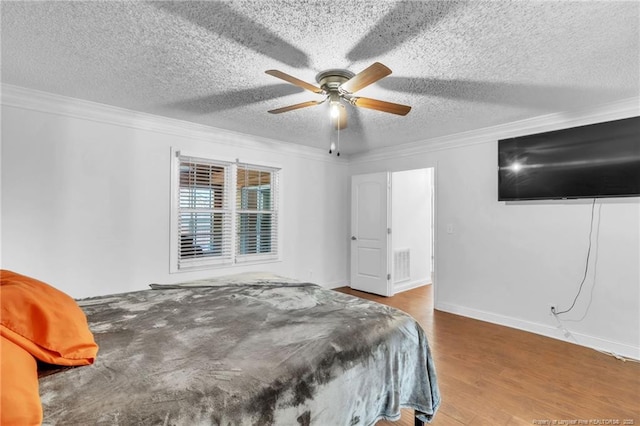 bedroom with visible vents, a textured ceiling, ornamental molding, and wood finished floors
