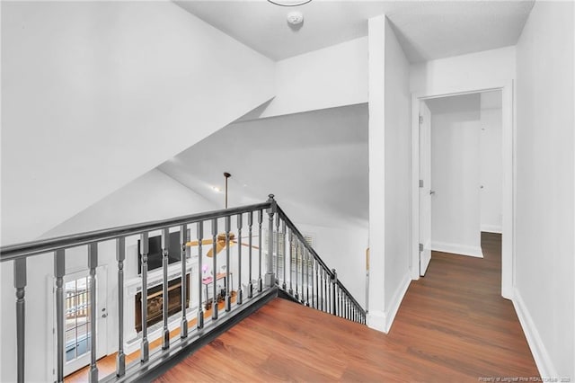 stairs featuring wood finished floors, baseboards, and lofted ceiling
