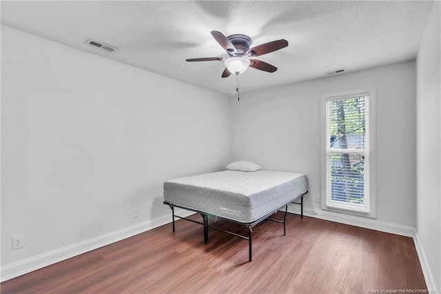 bedroom with visible vents, baseboards, and wood finished floors