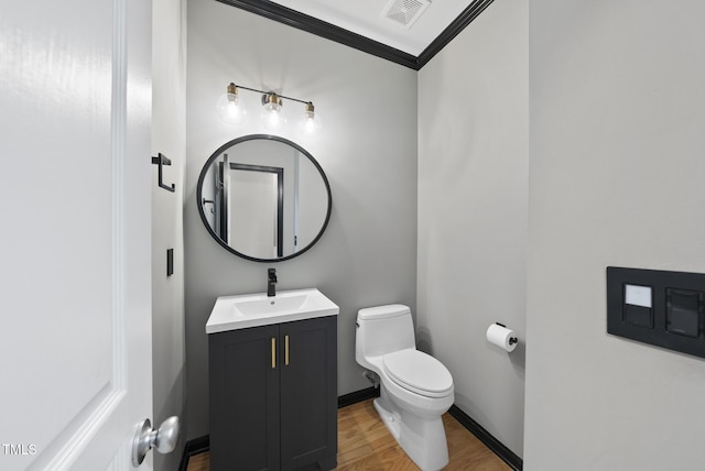 bathroom featuring vanity, ornamental molding, visible vents, toilet, and wood finished floors