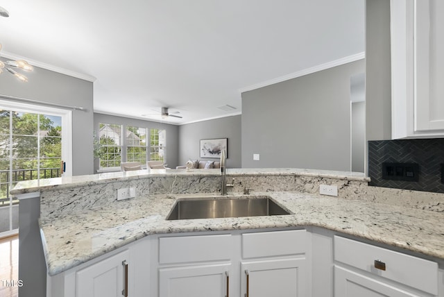 kitchen with ornamental molding, ceiling fan, a sink, and white cabinetry