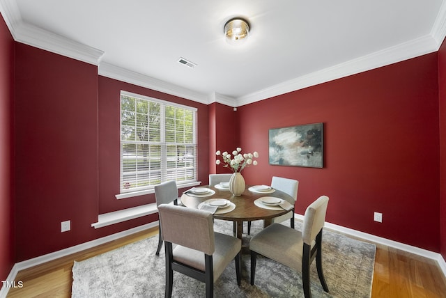 dining space featuring crown molding and wood finished floors