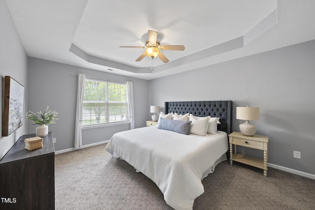 bedroom featuring a tray ceiling, ceiling fan, baseboards, and carpet