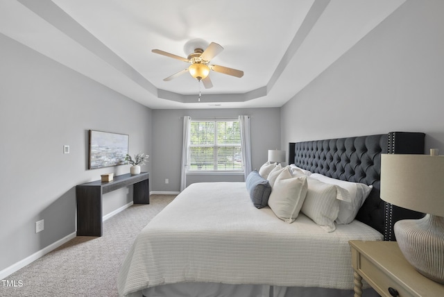 carpeted bedroom with baseboards, a ceiling fan, and a raised ceiling