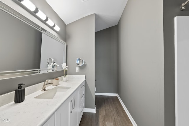 bathroom featuring toilet, wood finished floors, vanity, and baseboards