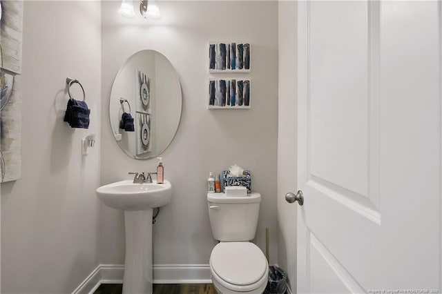 half bath featuring baseboards and toilet