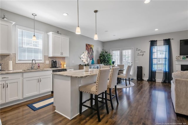 kitchen featuring tasteful backsplash, a center island, a sink, white cabinetry, and dark wood-type flooring