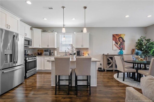 kitchen with a center island, dark wood-style floors, white cabinetry, and appliances with stainless steel finishes