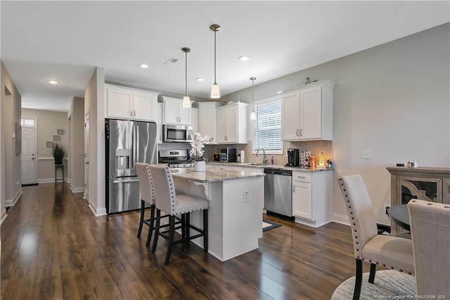 kitchen with tasteful backsplash, dark wood finished floors, white cabinets, and stainless steel appliances