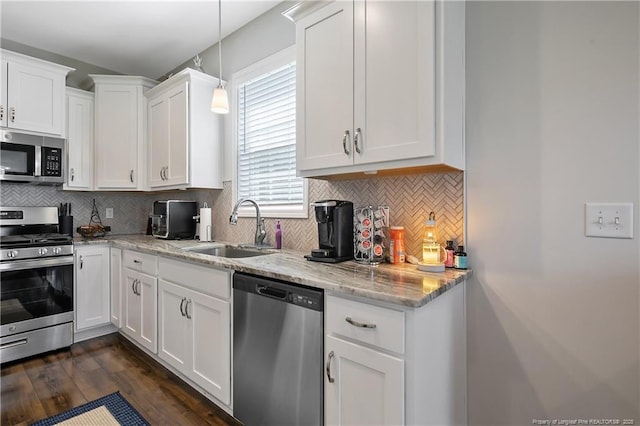 kitchen featuring tasteful backsplash, white cabinetry, light stone countertops, appliances with stainless steel finishes, and a sink