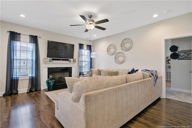 living area featuring baseboards, a ceiling fan, a fireplace, recessed lighting, and dark wood-type flooring