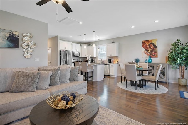 living area with dark wood-type flooring, a ceiling fan, and recessed lighting